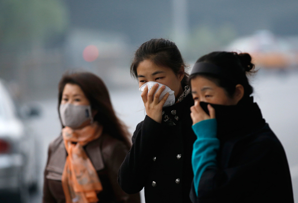 Women wear masks while waiting for bus during a smoggy day in Beijing, October 28, 2013.  Schools to be closed for air pollution
