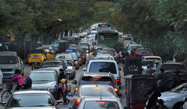 Pedestrians move through parked and running vehicles near South Third Ring Road in Beijing, Nov 14, 2013. Epic shortage of parking in Beijing